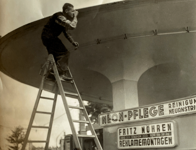 Historisches Foto: Firmengründer bei der Reklamemontage